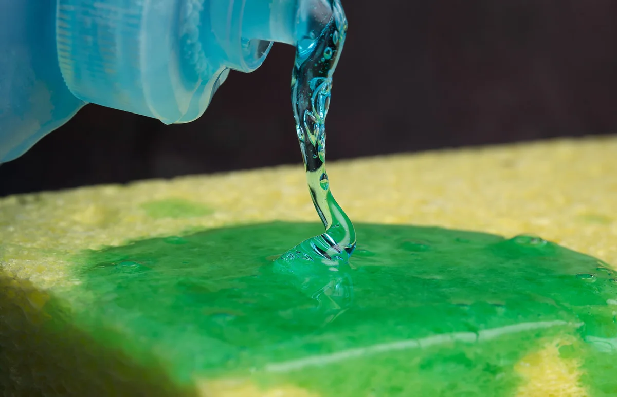 Close-up of dishwashing liquid being spread on cleaning sponge
