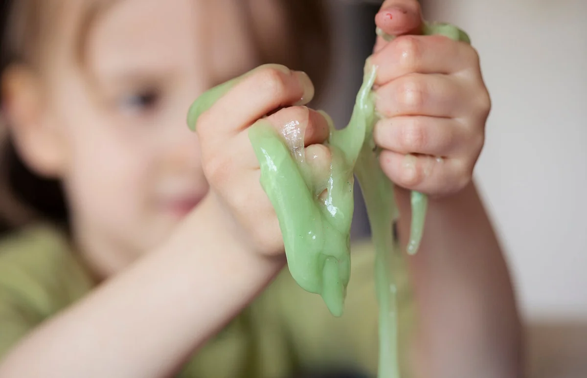 Child squeezing novelty green slime through fingers