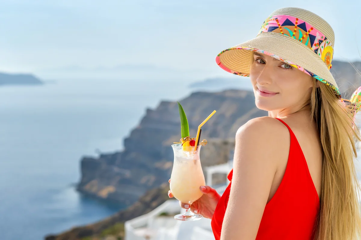 Woman holding pina colada cocktail and enjoying the view