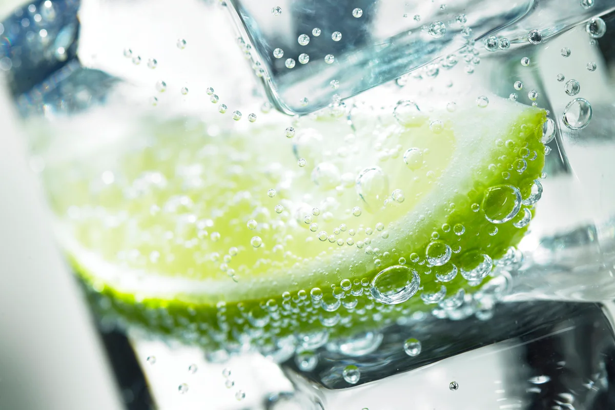 A slice of lime with ice in a sparkling drink