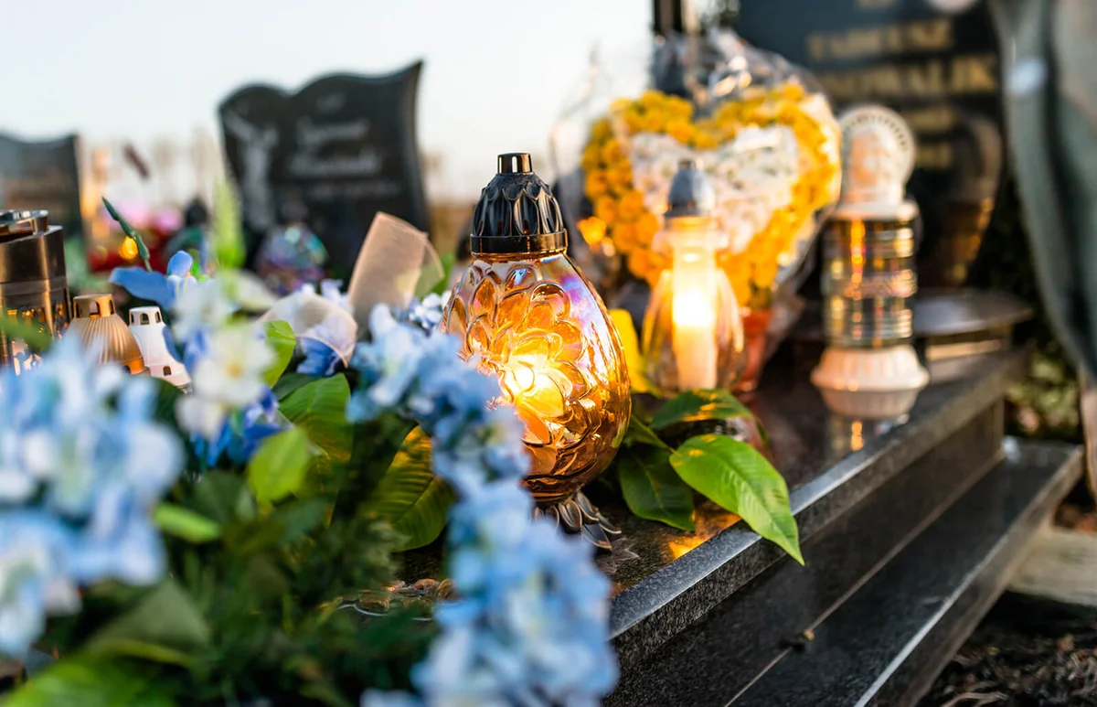 Artificial flowers and candlesticks lie on the tombstone in the cemetery