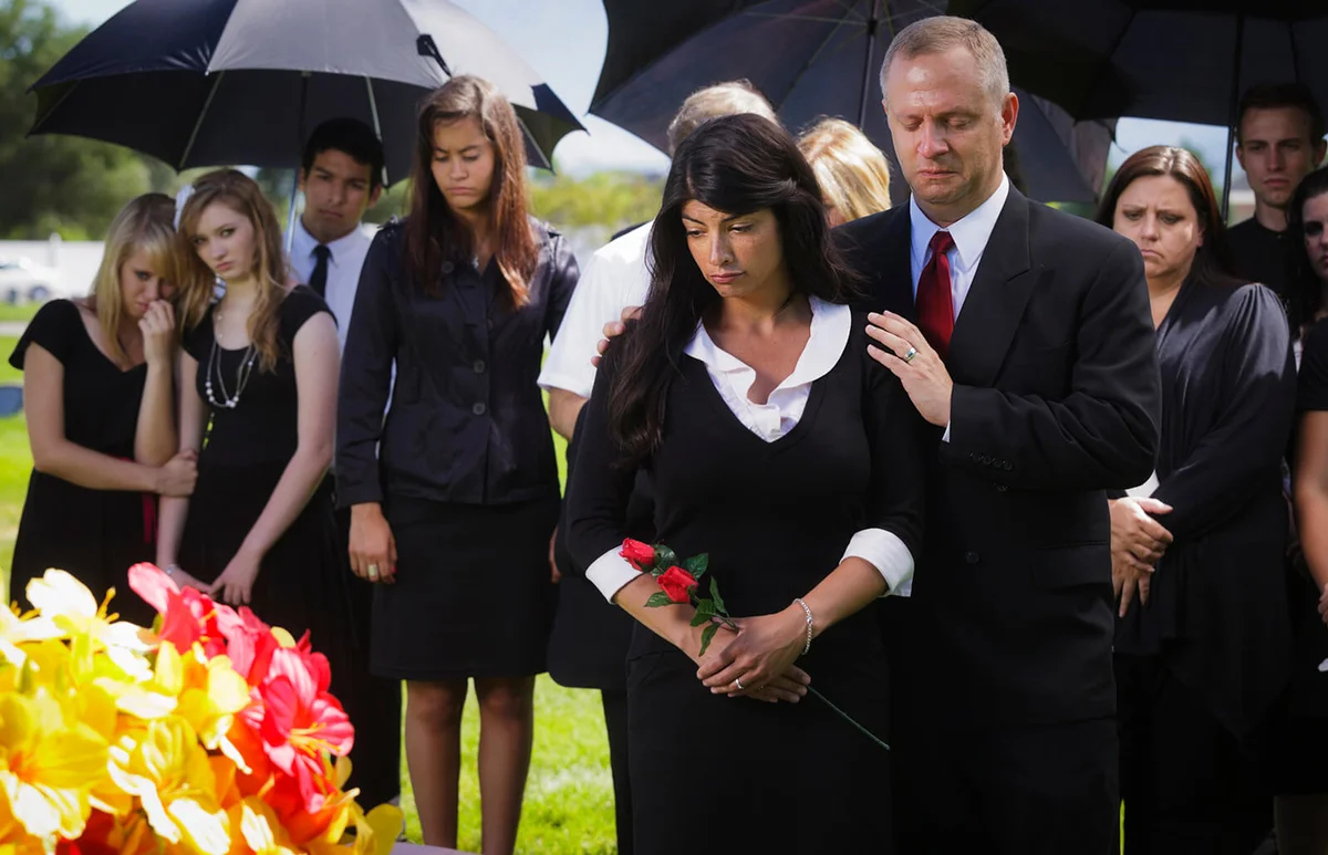 grieving family standing graveside at a funeral