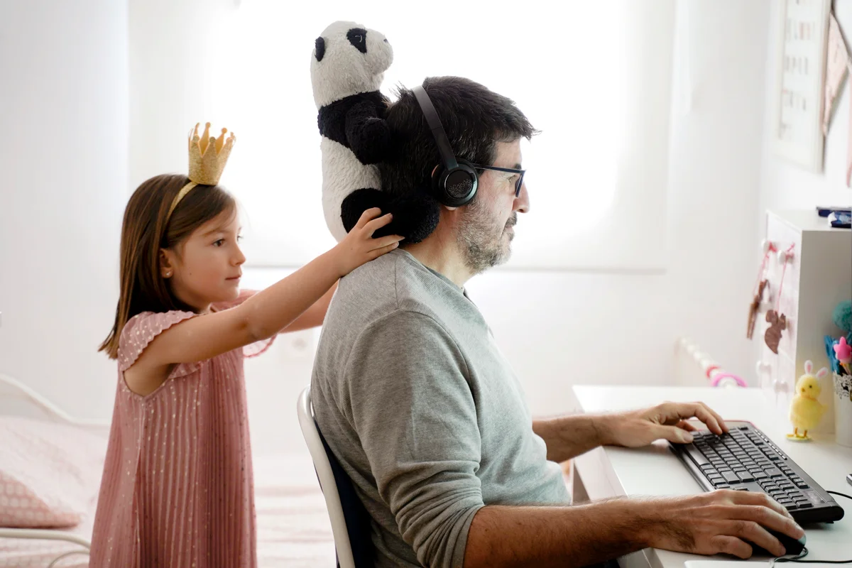 Man doing telework and a little girl playing around