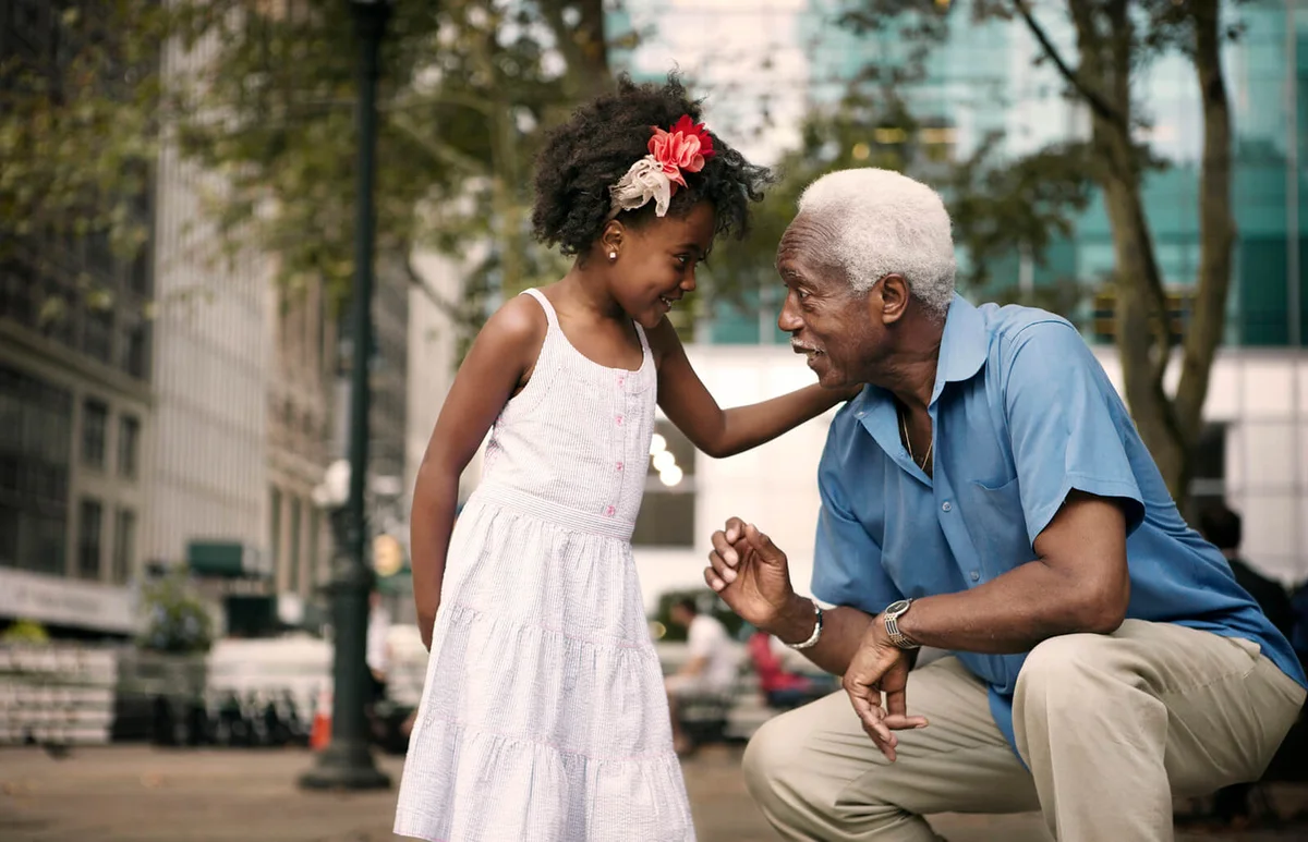 Granddaughter talking to grandfather while sitting in city
