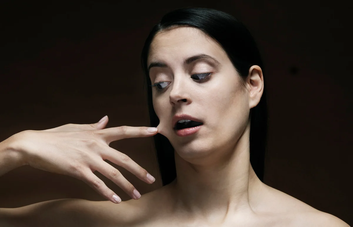 young woman with her finger glued to her face