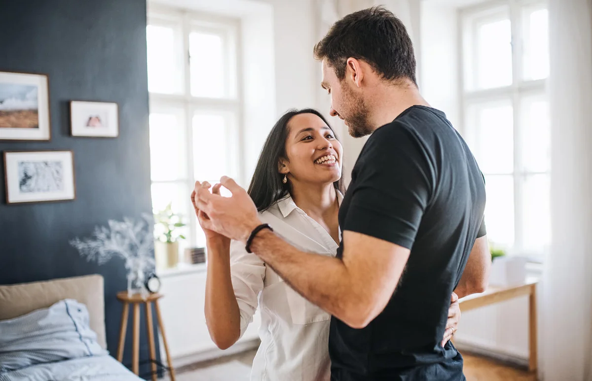 Affectionate young couple in love dancing at home