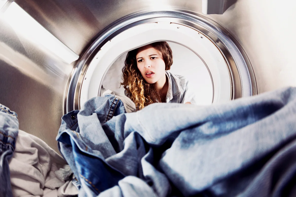 Woman looking unhappy as she reaches in for the laundry