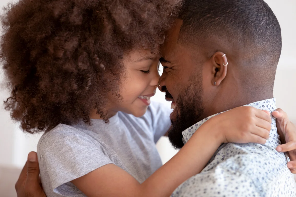 Cute daughter embrace touch noses with happy dad