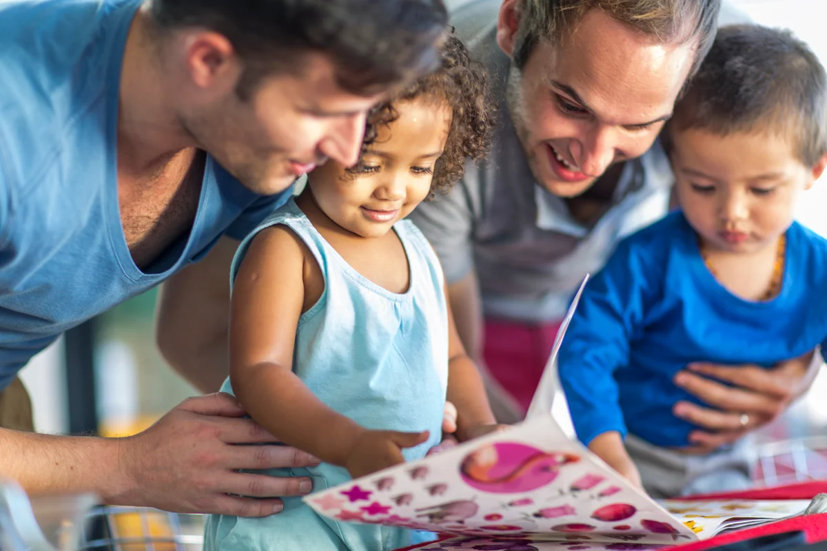 Two men with two kids looking at picture book