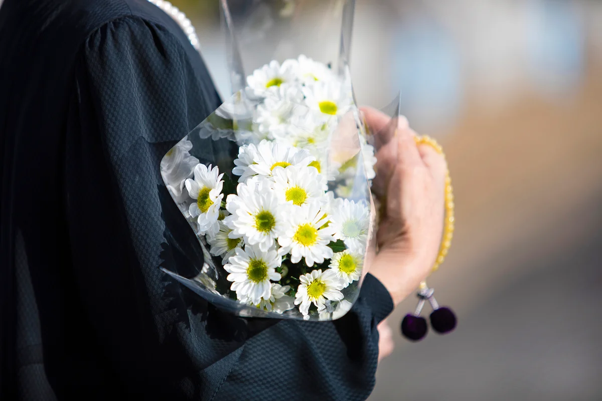 Woman holds old white chrysanthemum and beads in her hands