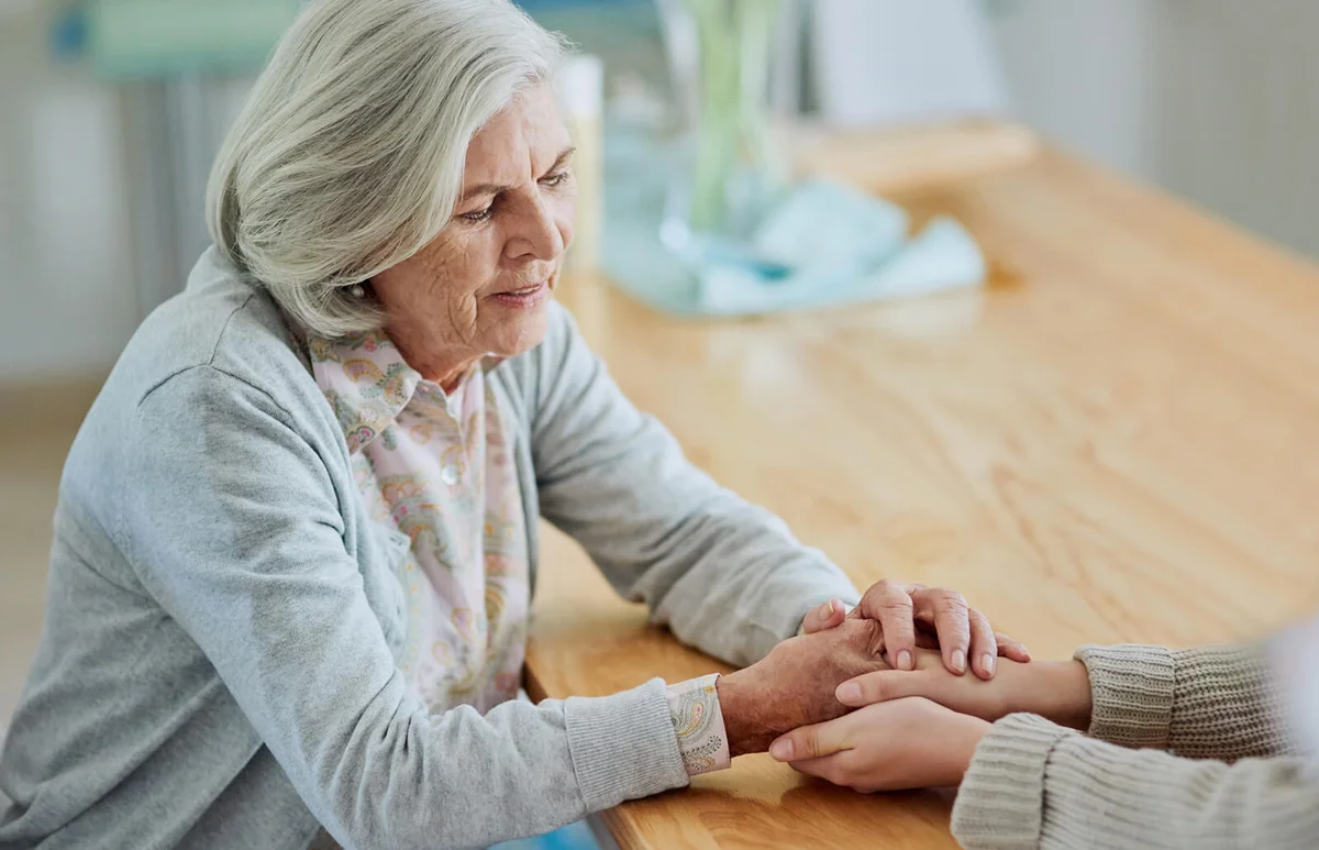 senior woman holding the hands of her unrecognizable daughter