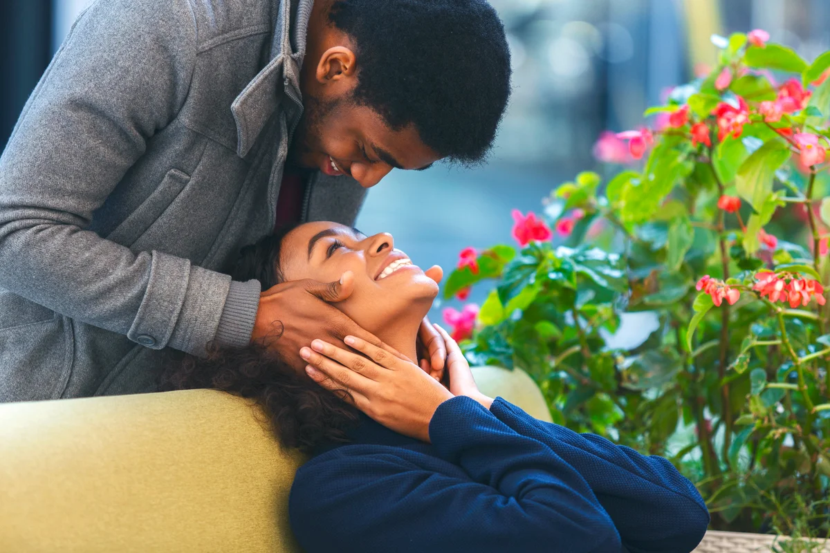 Man staying behind woman and touching her face while smiling