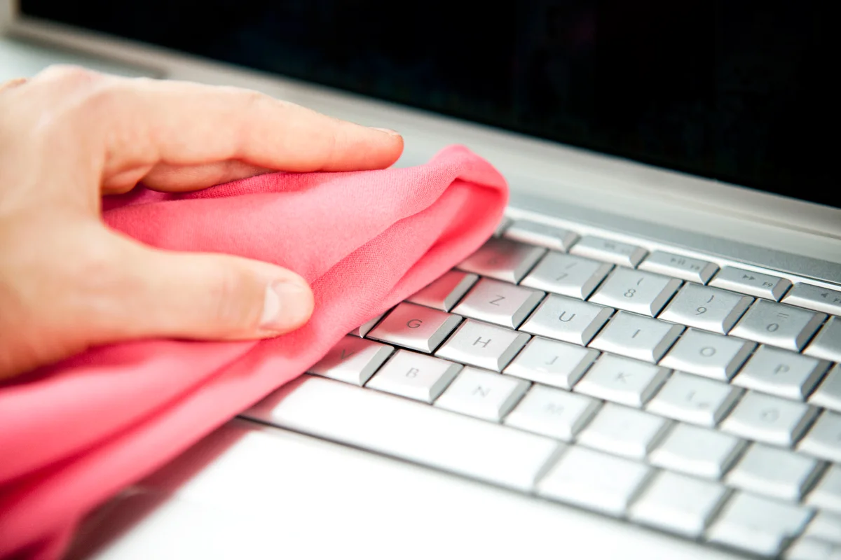 Woman cleansing laptop with duster