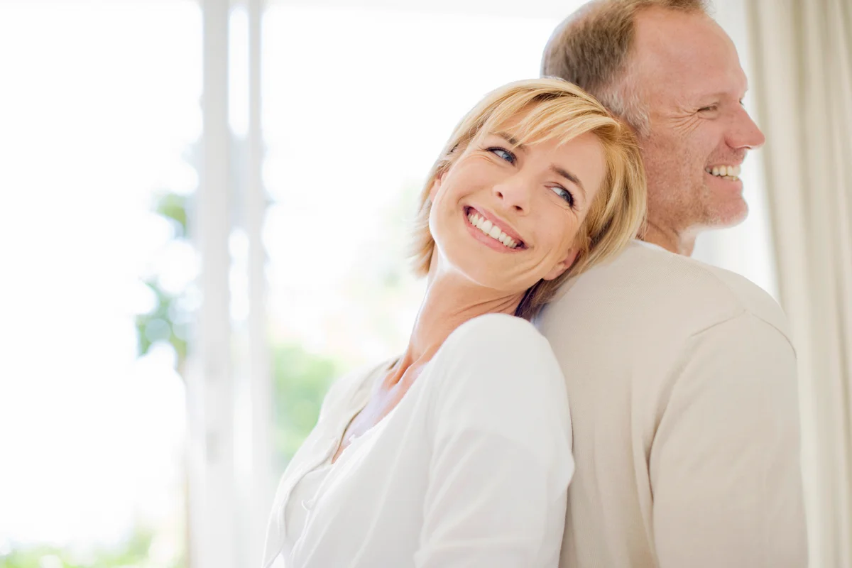 Couple standing back to back and smiling