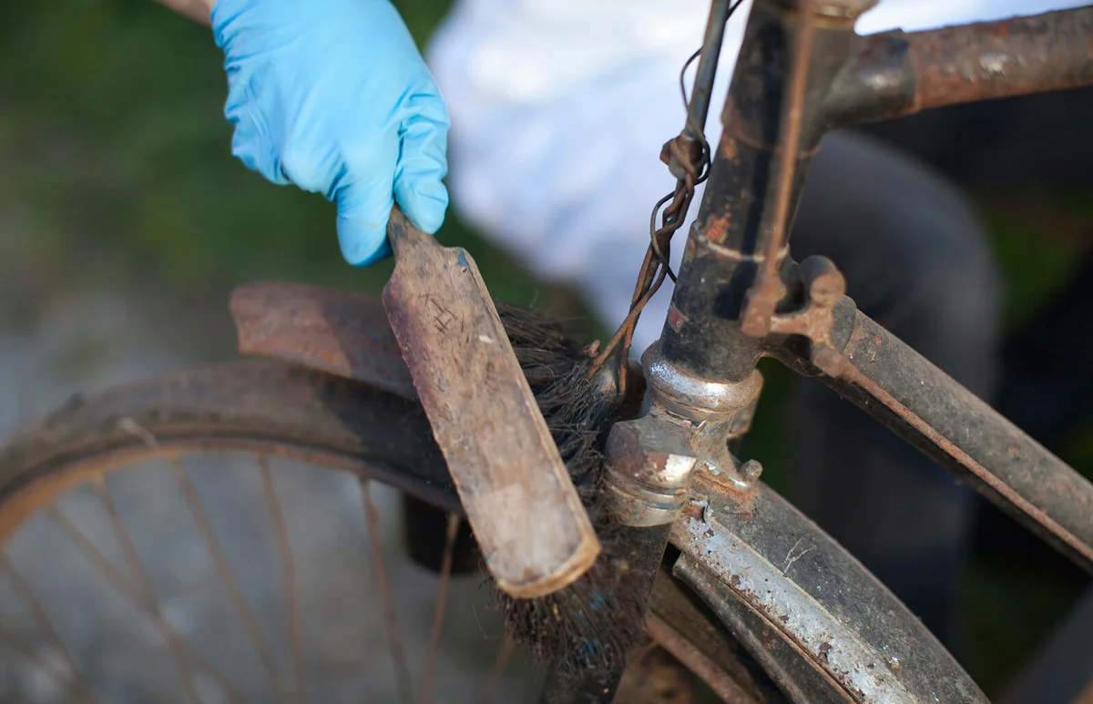 woman cleaning rust from vintage bicycle