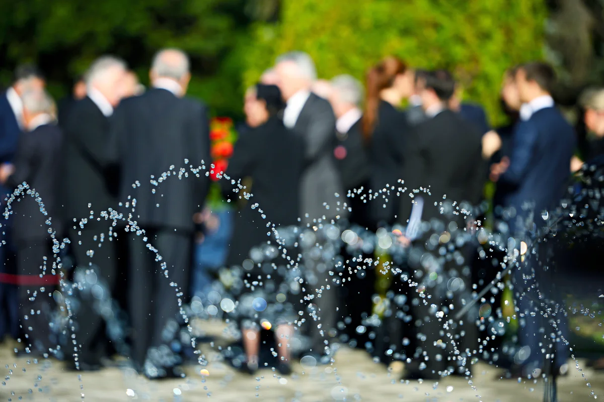 People in blur wearing black suits at wake