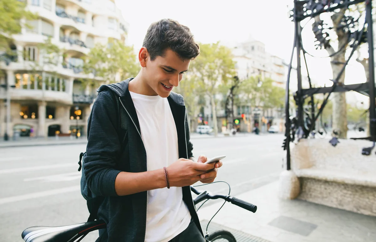 Teenager with a bike in the city, using smartphone