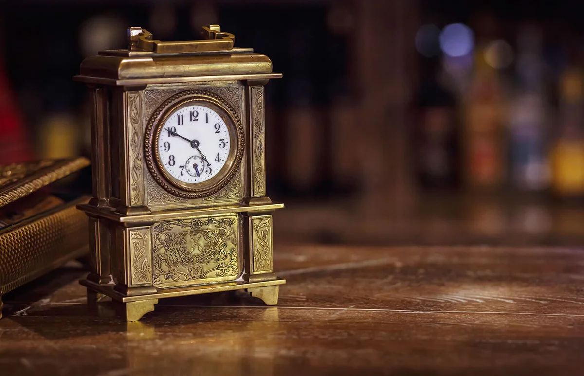 antique clock stands on a wooden table