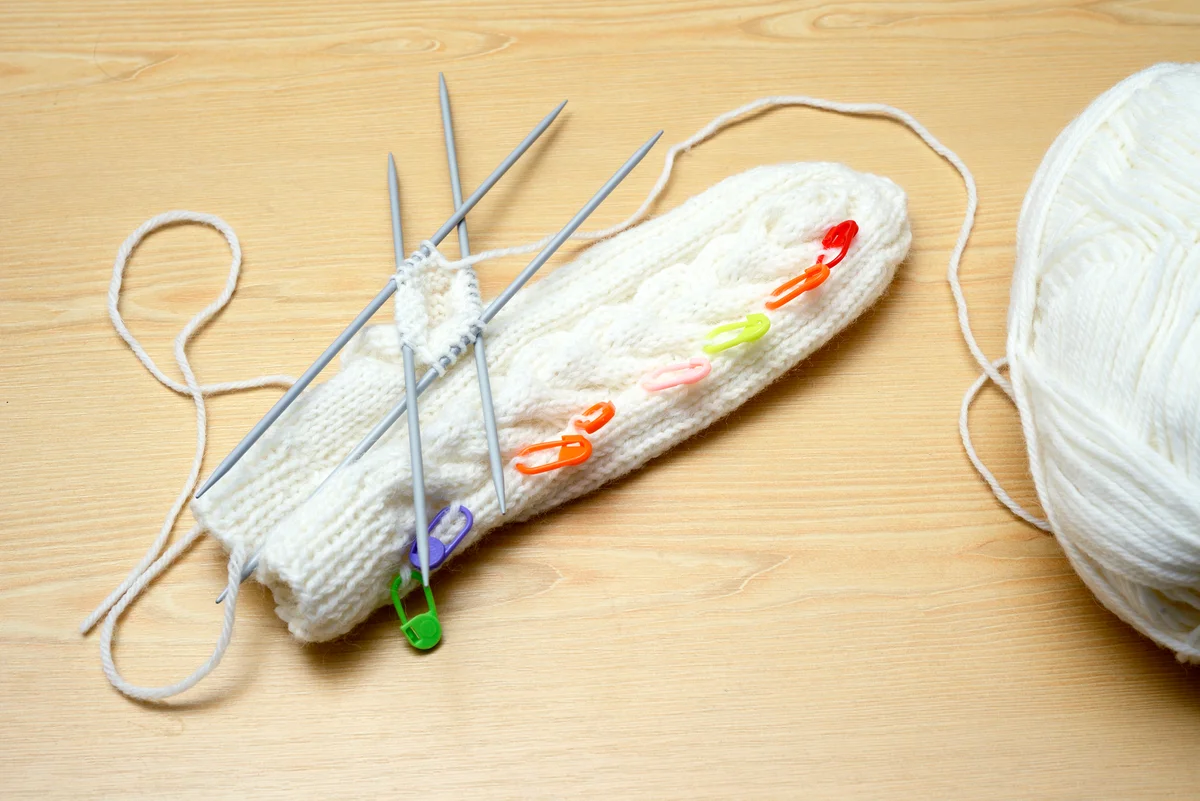White mittens and knitting needles