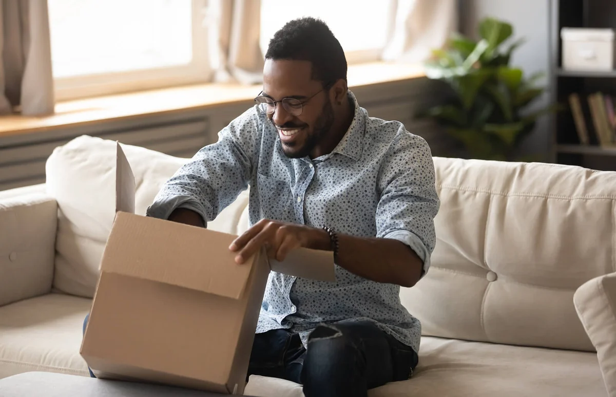 man customer opening cardboard box parcel on sofa