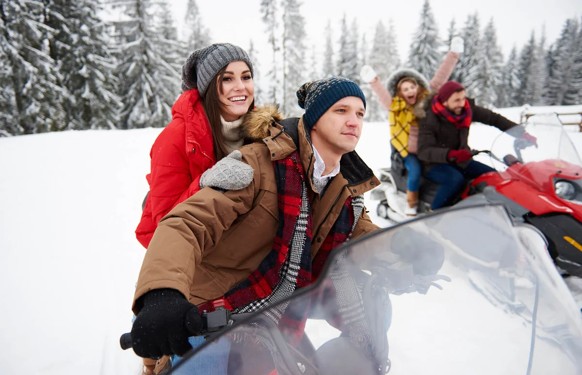Friends riding snowmobiles in winter