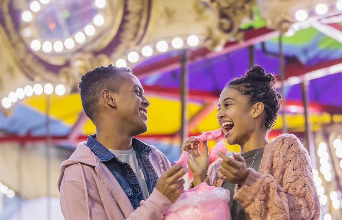 Young couple at carnival eating cotton candy