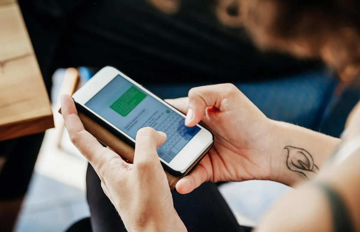 woman messaging her friends using her smartphone in a cafe