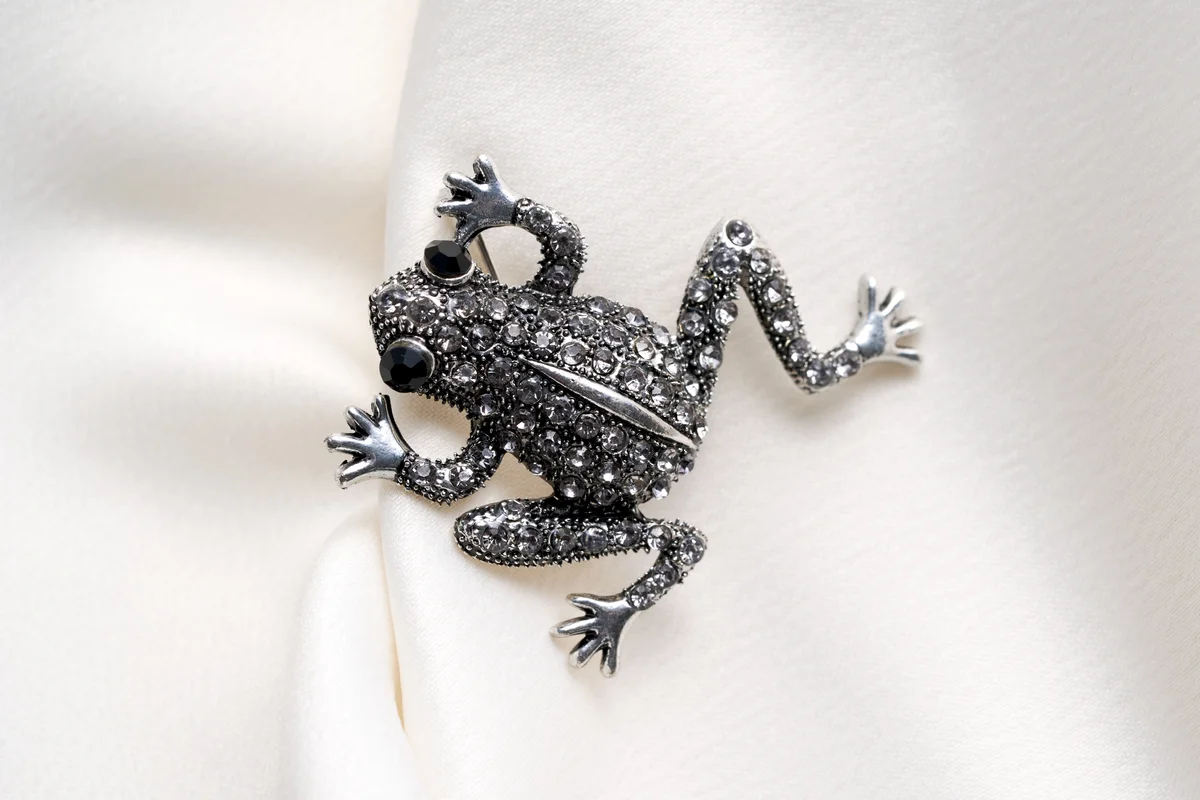 Silver brooch shaped like a frog with small rhinestones