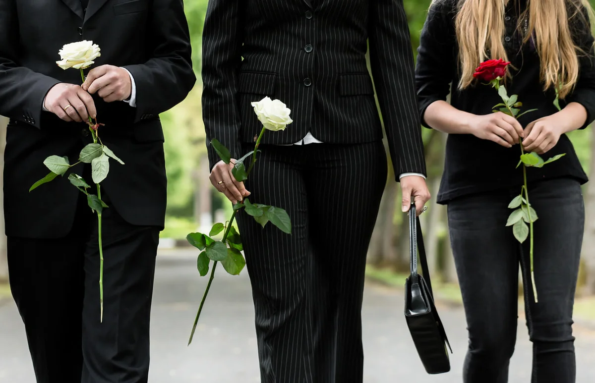 Family holding roses on road during funeral