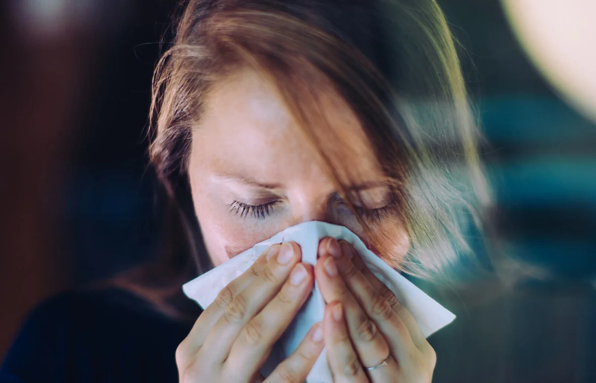 Woman sneezing behind a window