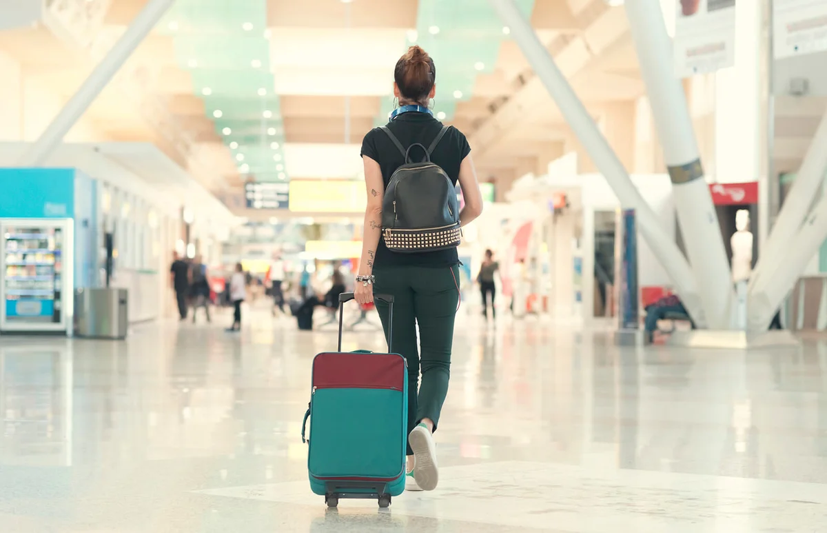 woman pulling her luggage strolling inside the airport