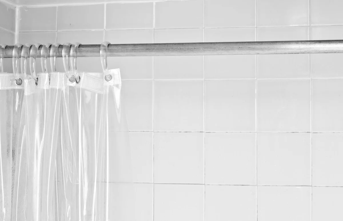 Clear shower curtain with a white tile shower