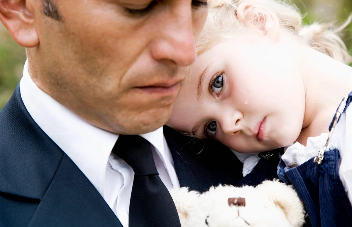 Man carrying a sad small child