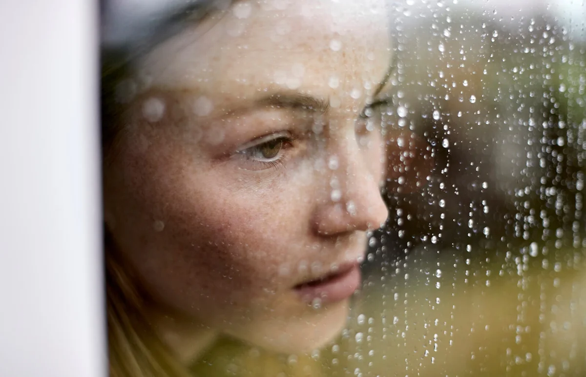 pensive young woman looking out of window