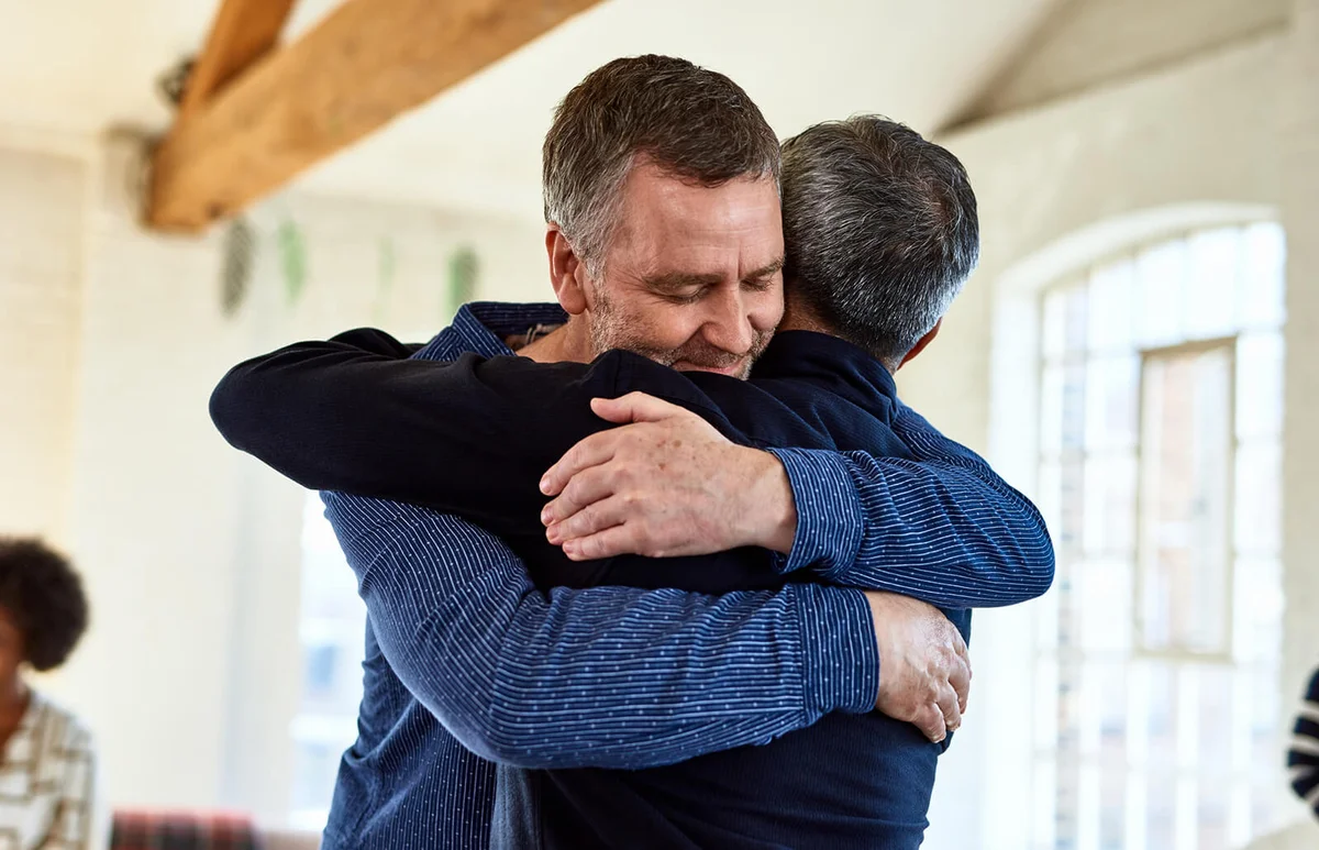 mature friends embracing with arms around each other