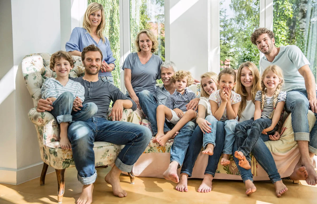 Group portrait of family and friends sitting on sofa in living room