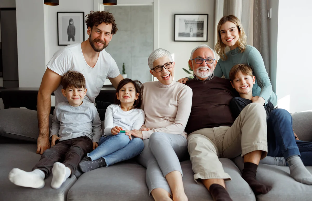 Multi generational family is posing on the sofa in their living room