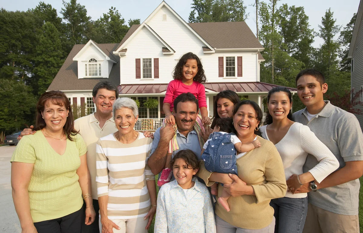Multi-generational family smiling in front of house