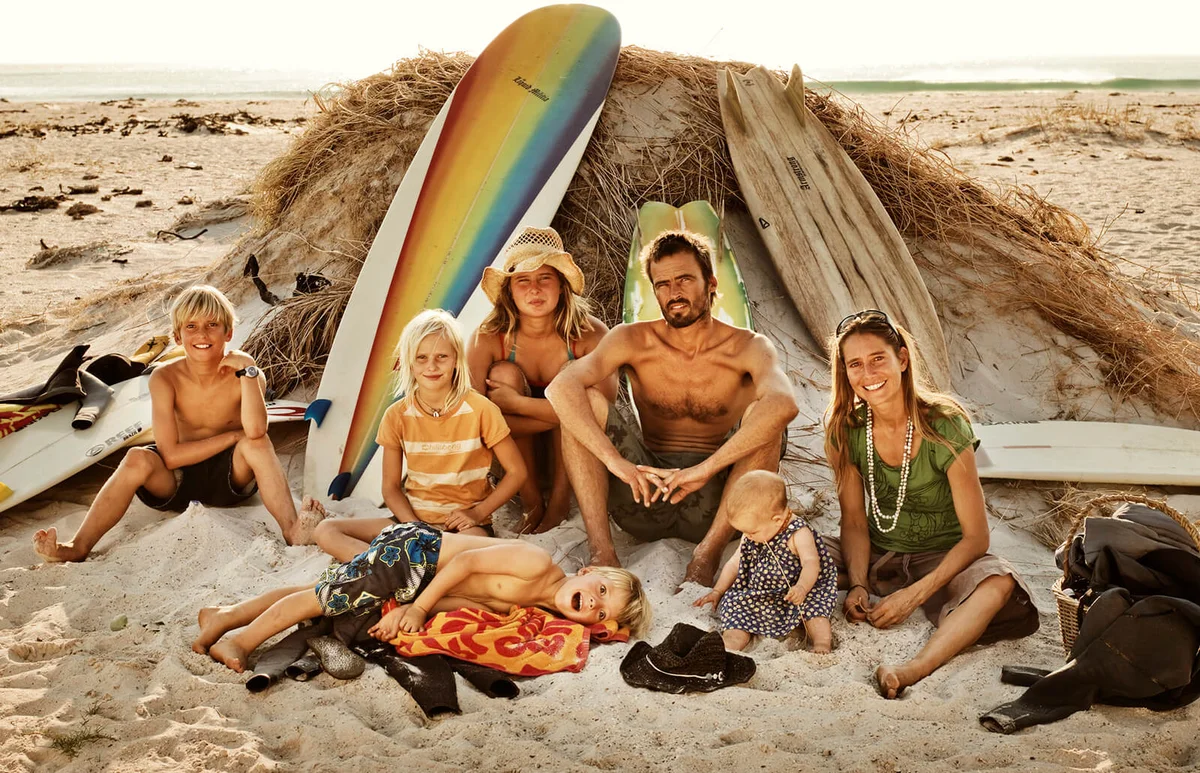 Family sitting on the beach with surf boards