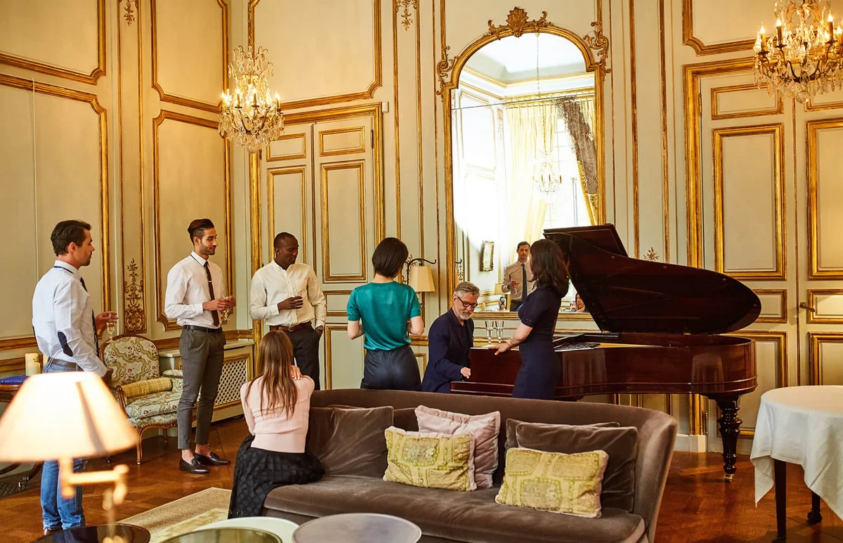 group of friends listening to a piano player at a party in an elegant home