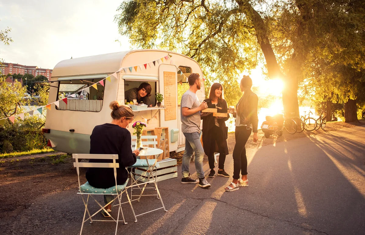Owner looking at customers standing on street through food truck window