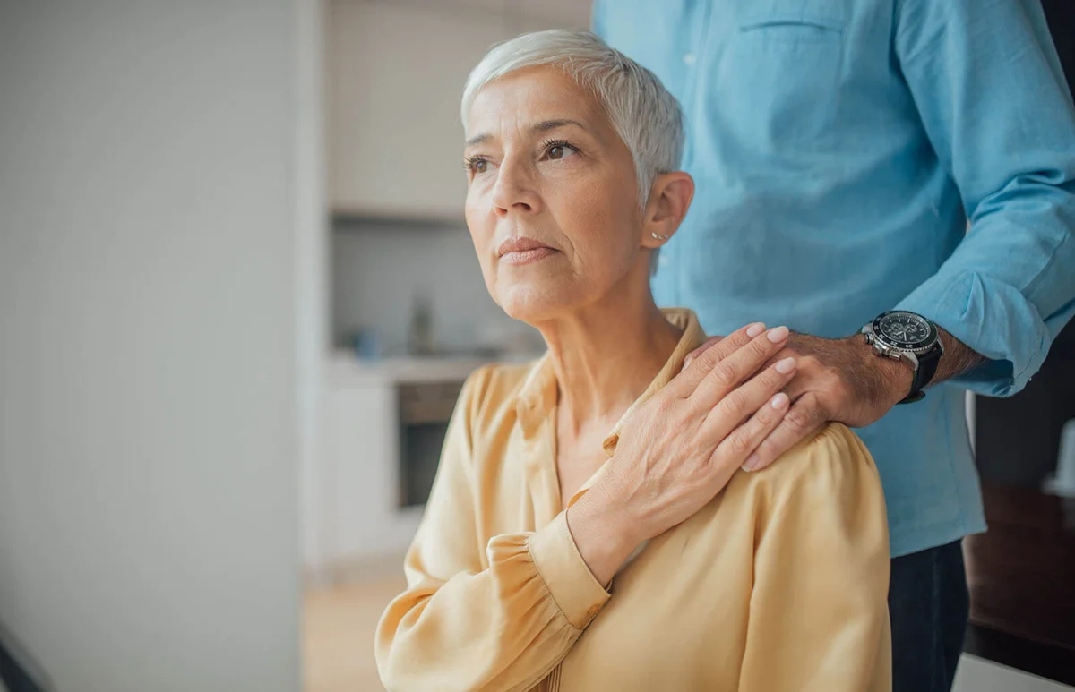 Worried woman with male hand on her shoulder