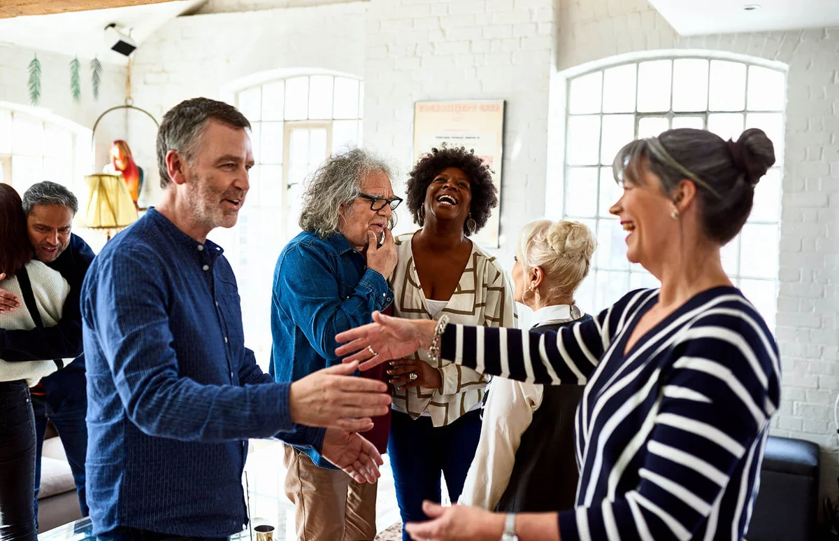Mature friends greeting each other at social gathering
