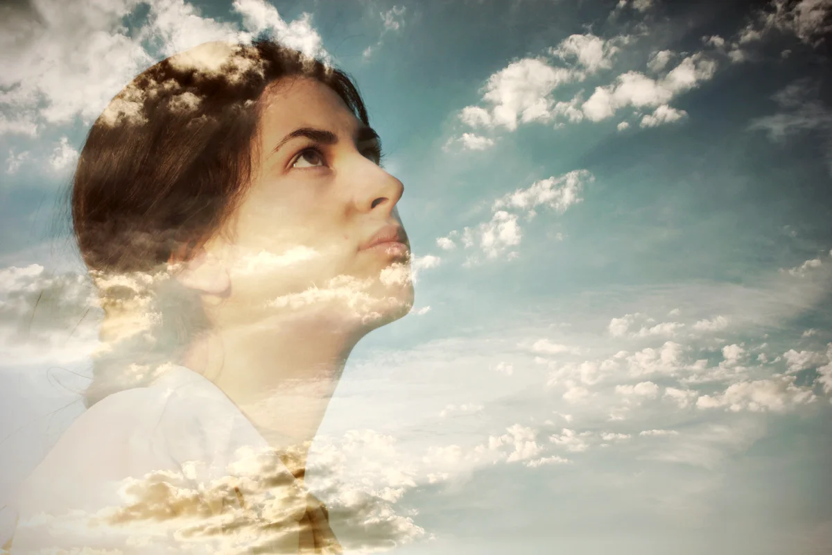 Pensive young woman and cloudy sky
