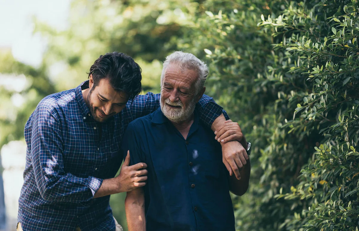 old man and his son are walking in the park