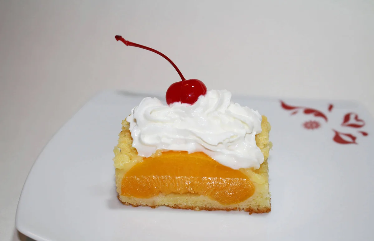 Peach cake with cream and cherry