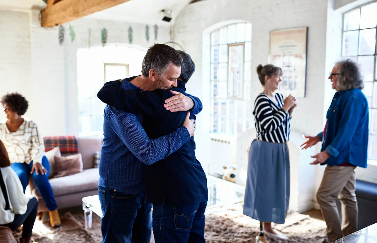 Mature male friends hugging at party