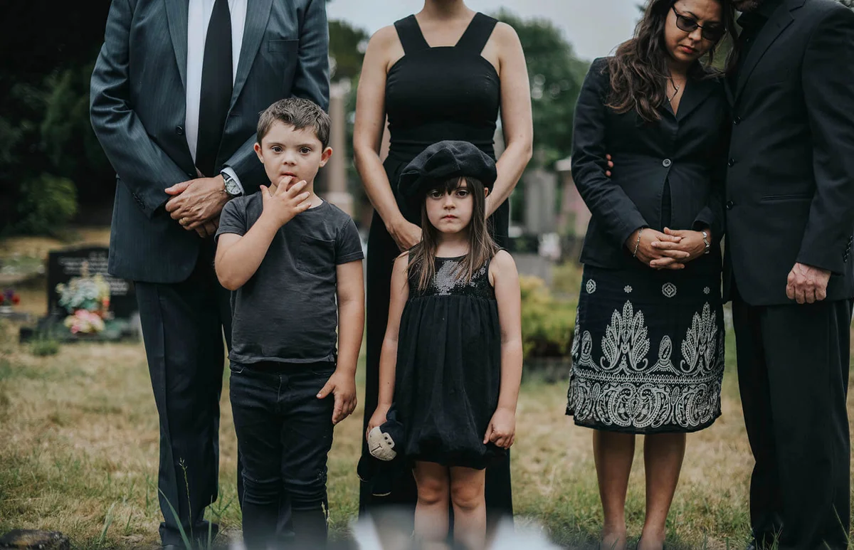 Sad grandkids standing by the grave