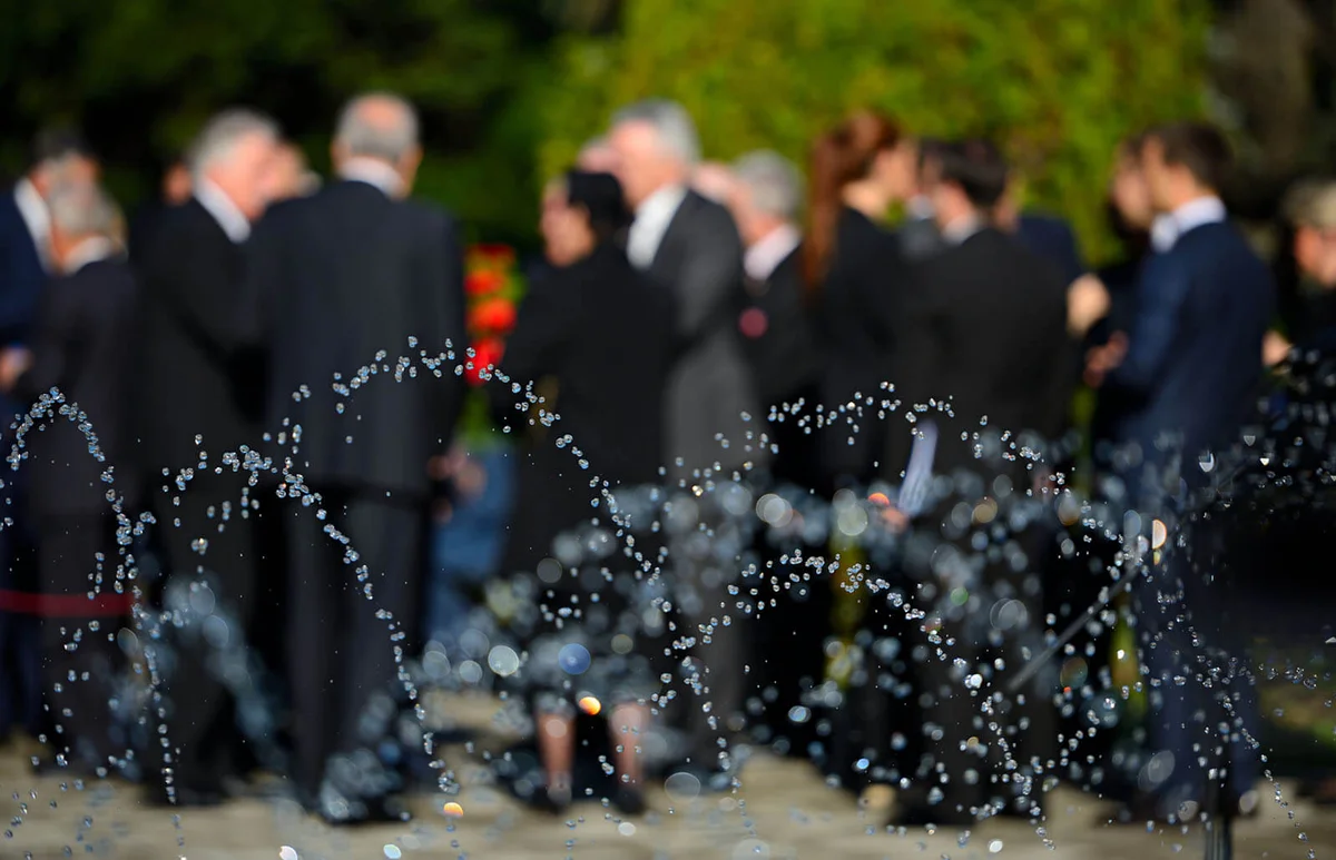 Water Spraying Against People At Cemetery During Funeral