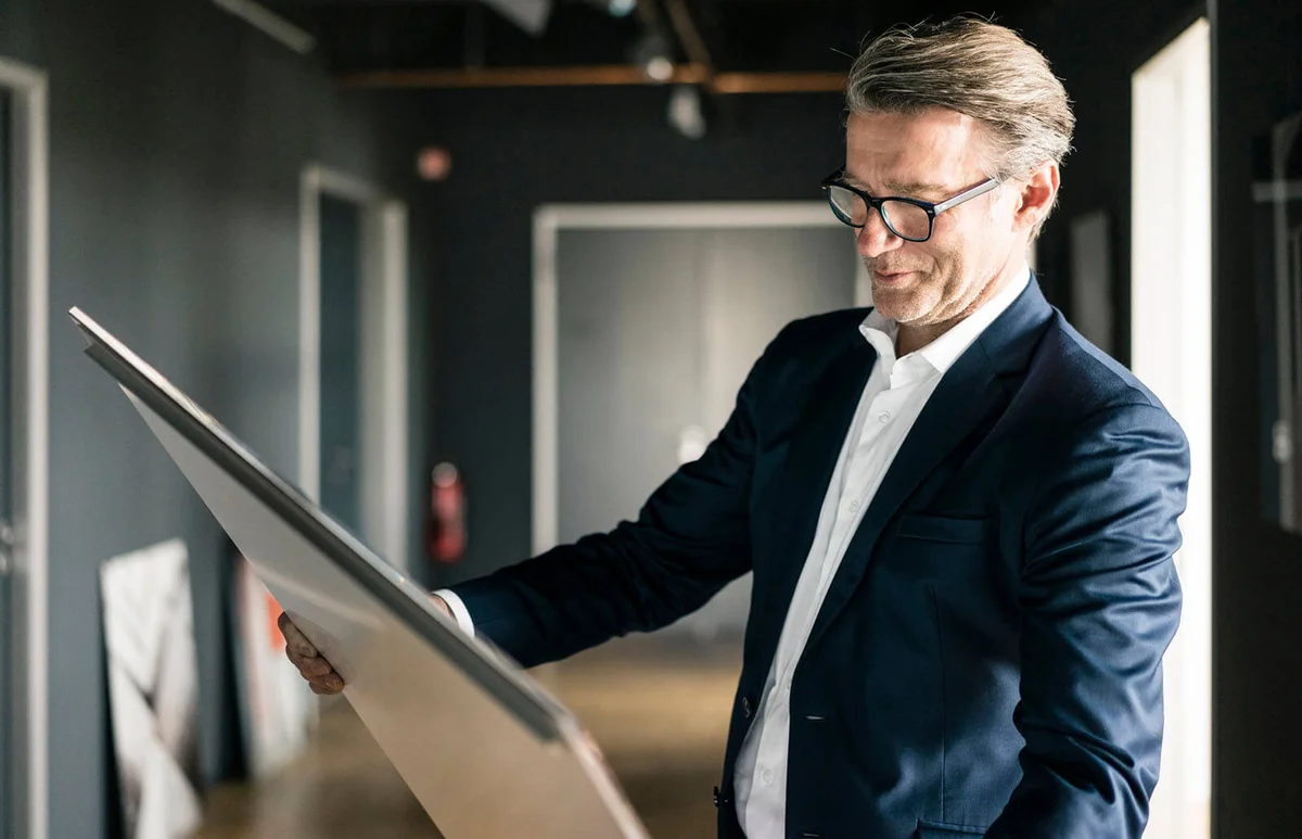 man in office looking at painting